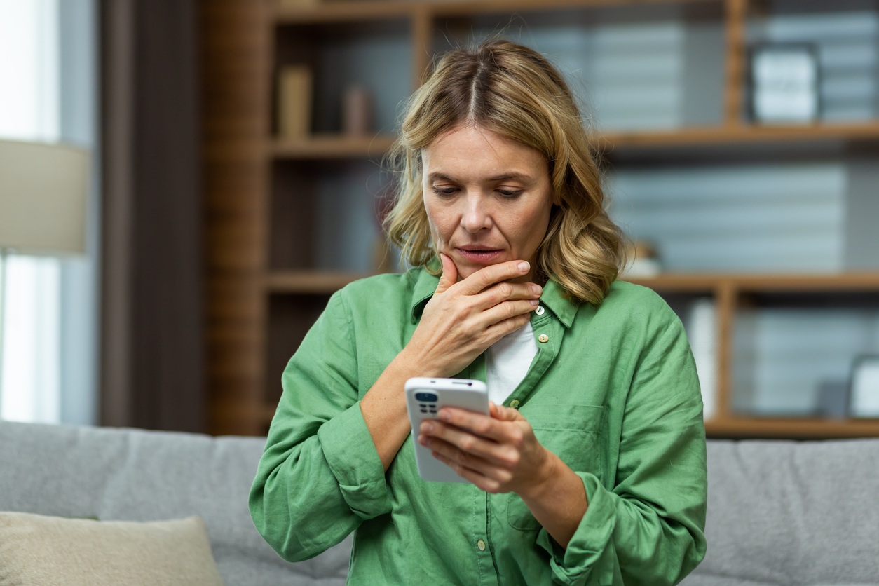 Vrouw kijkt naar telefoonscherm en begrijpt niet wat ze leest.
